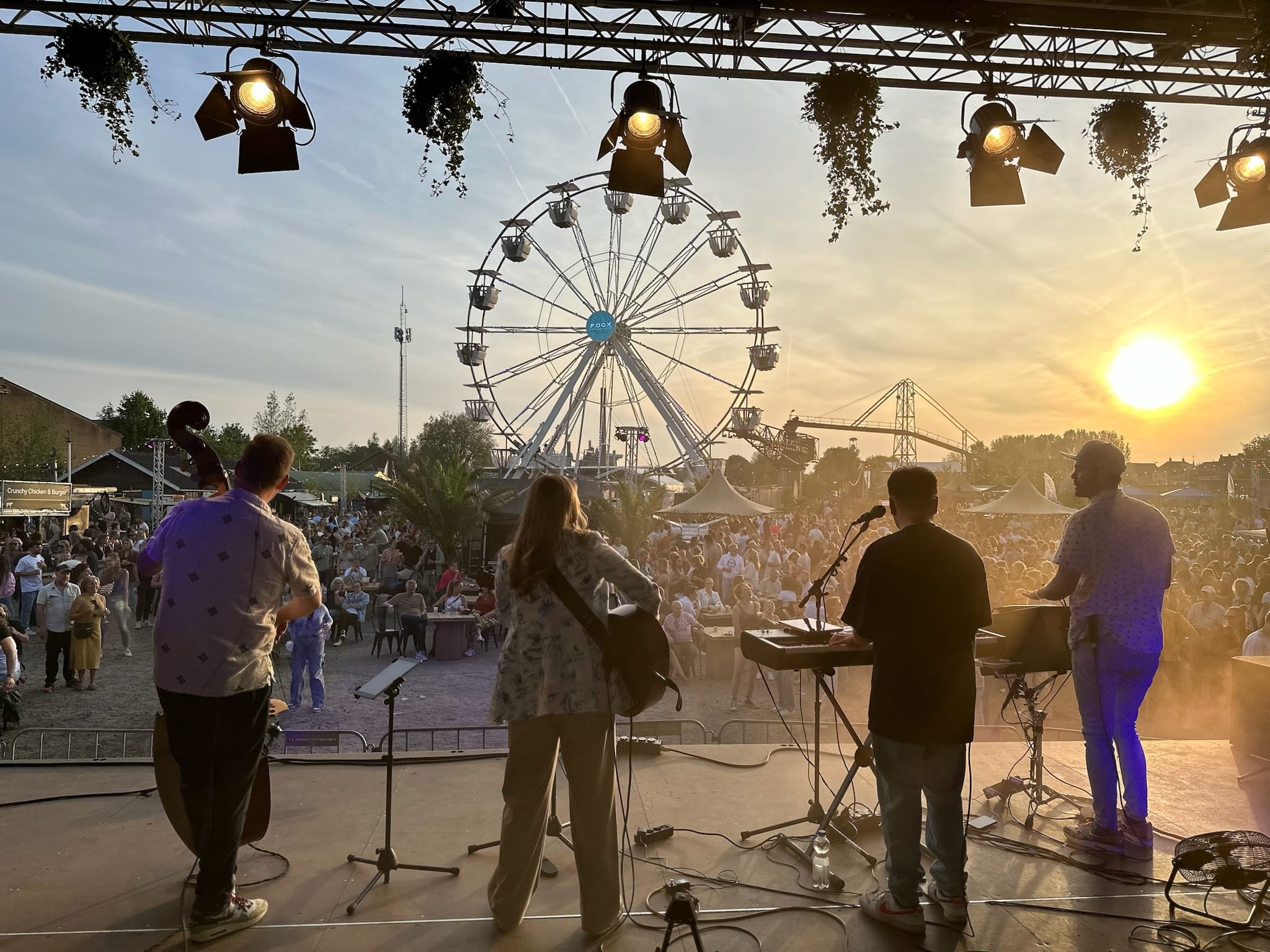 Band speelt voor groot publiek bij zonsondergang.